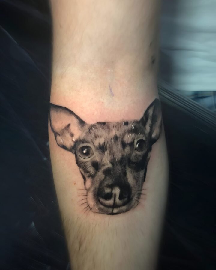 Retrato realista de un perro tatuado en el antebrazo